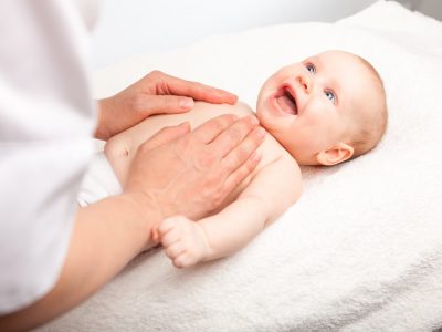 Three month baby girl is receiving chest massage from a female massage therapist