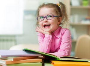 Smart-kid-girl-in-eye-glasses-reading-books-in-her-room